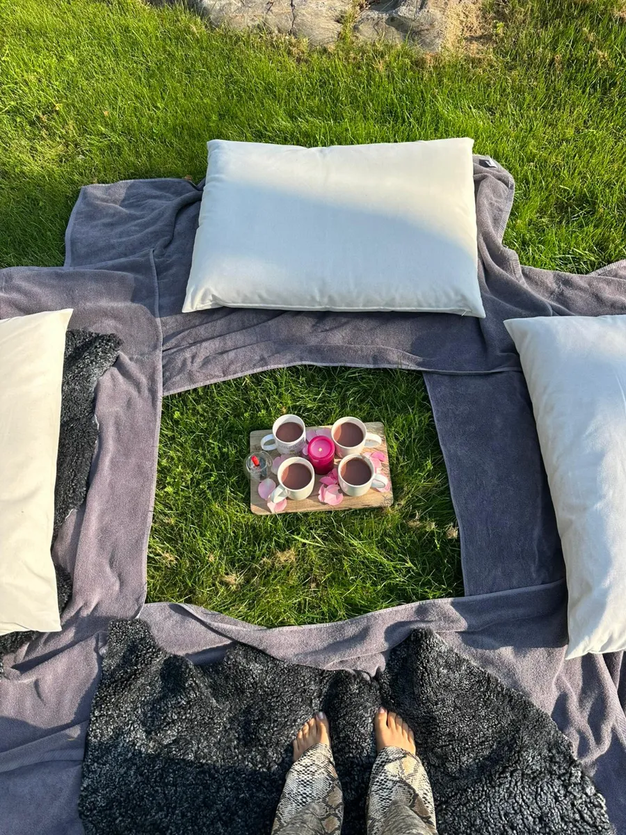Cushions and cacao laid out for a ritual on the grass