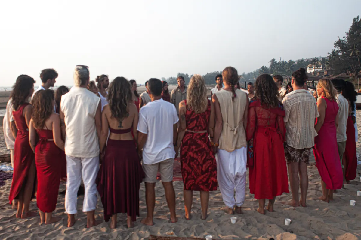 Men in white and women in red, facing the sea