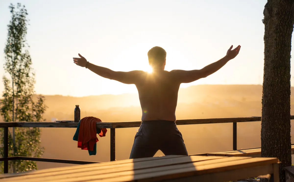 A man with arms open to the sunrise